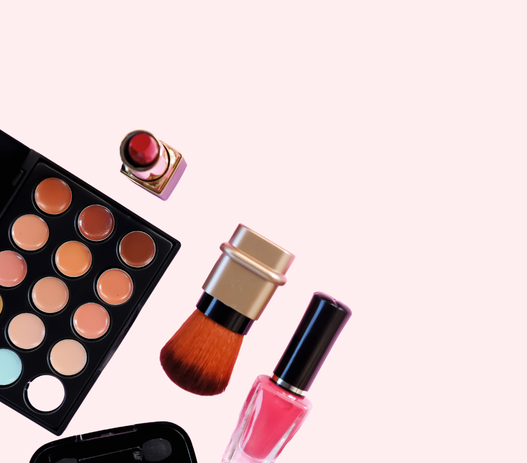 A photo of makeup items. There is a multi-coloured make up palate, red lipstick, blush brush, eye makeup and pin nail polish coming from the bottom left side of the photo.