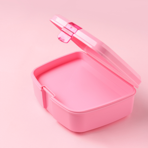 An empty, pink lunch box in front of a pink background