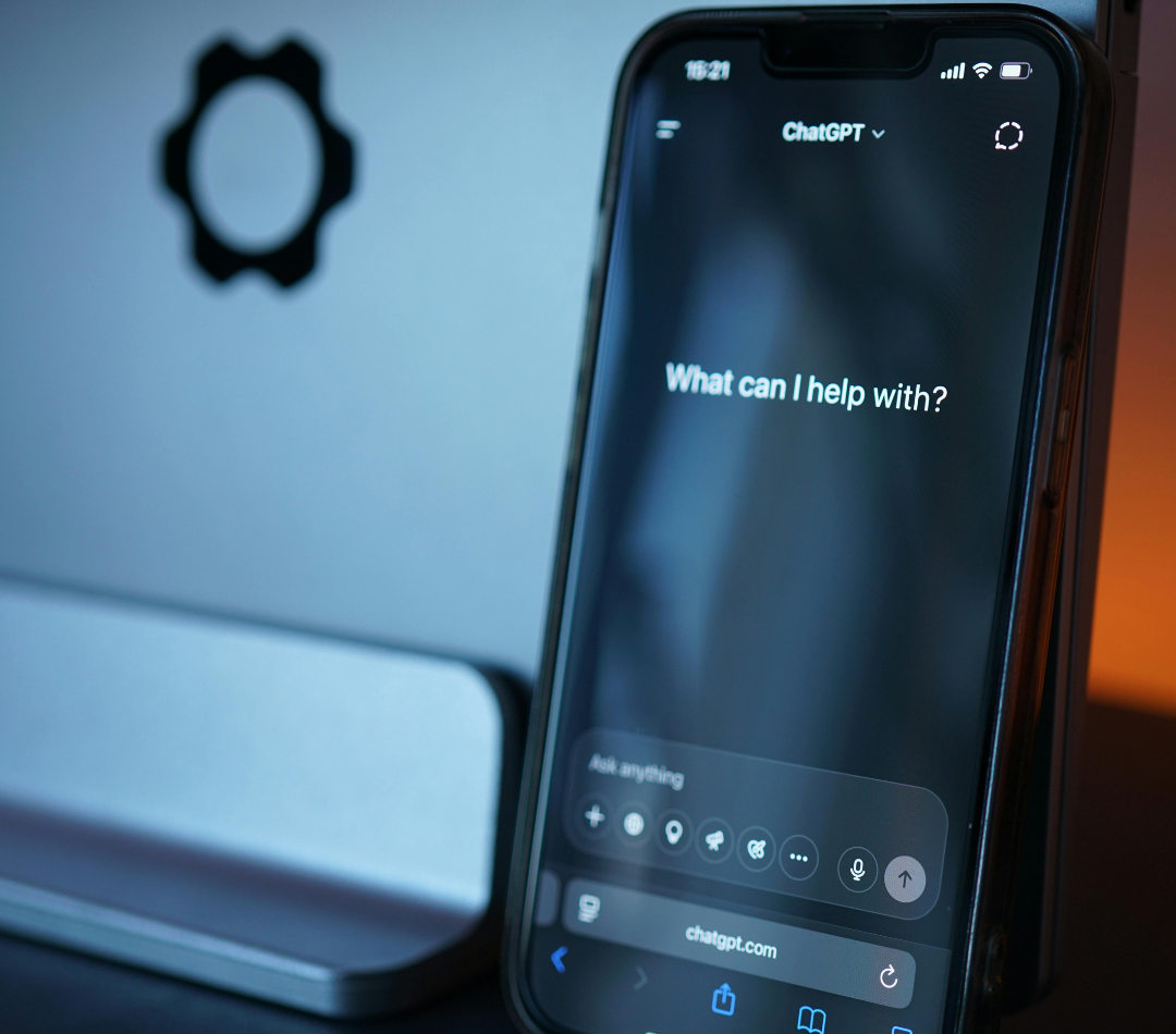 A photo of a phone or tablet open to an AI chat box asking 'what can I help with?'
