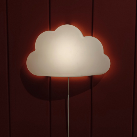 A cloud shaped night light hanging on a red wall.